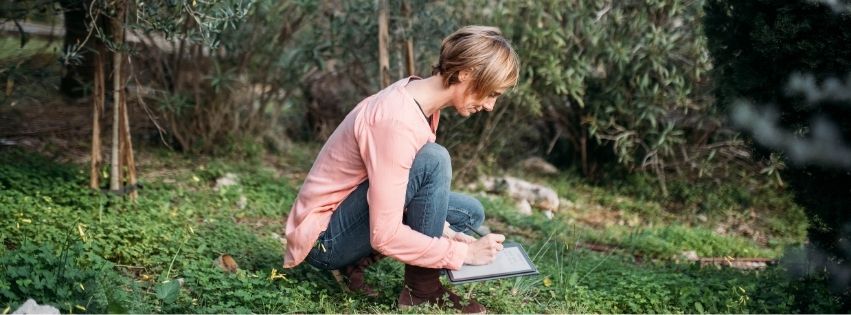Frau schreibt in ein Naturjournal im Grünen