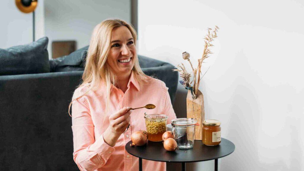 Zwiebel-Hustensaft selber machen: Person löffelt Zwiebelsaft aus dem Glas – Hausmittel bei Erkältung und Hustenreiz