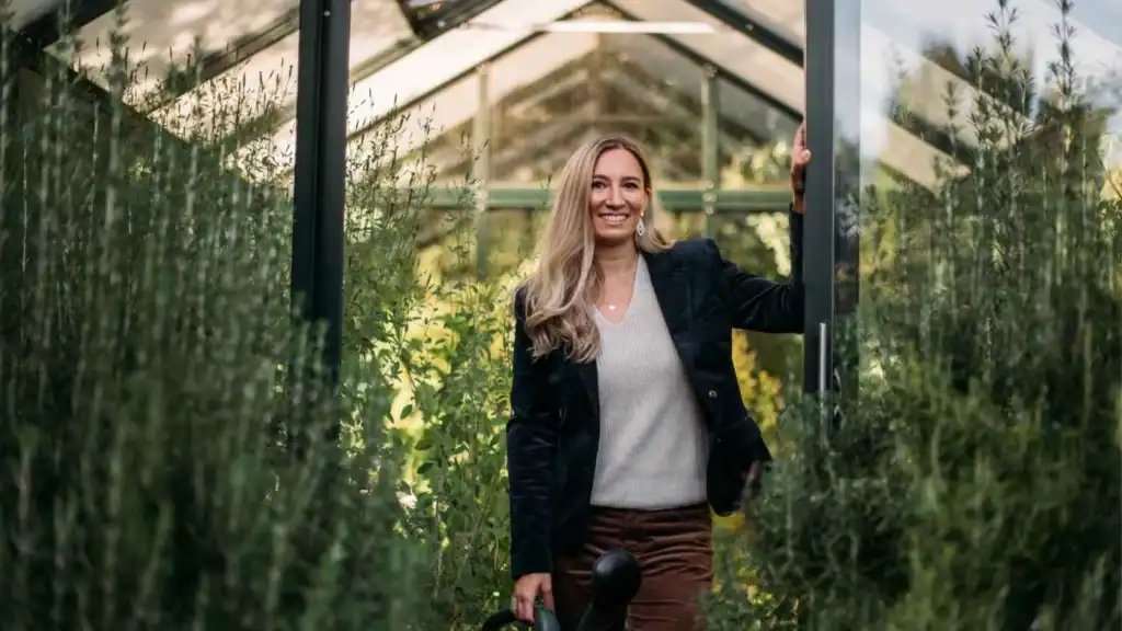 Patricia im Grünhaus mit Heilpflanzen im Hintergrund