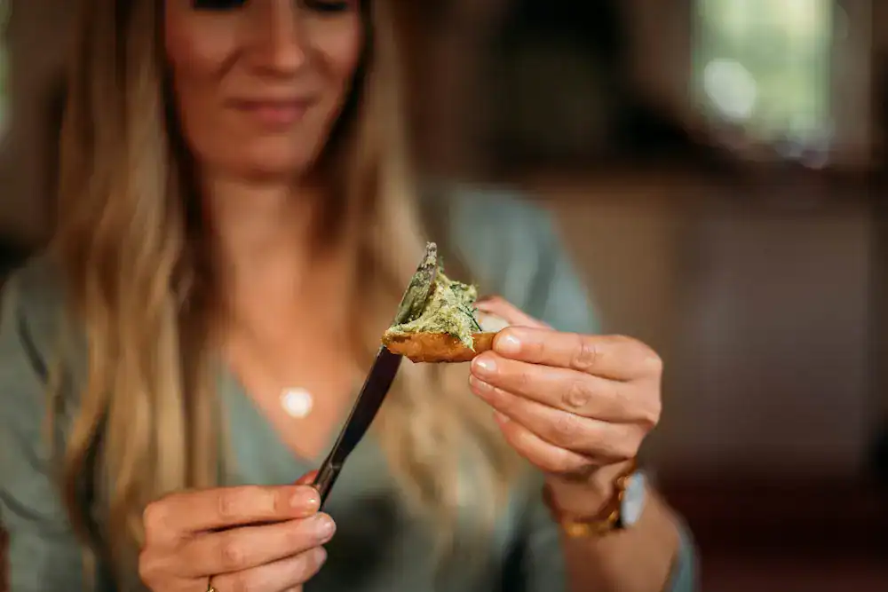Frau isst Kiefernnadelpesto auf einem Stück Brot